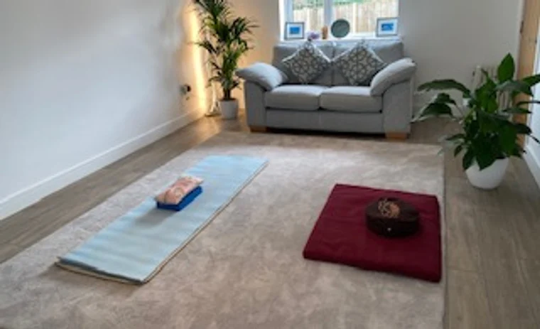 A quiet room set up with a mat, cushion, and singing bowl for meditation